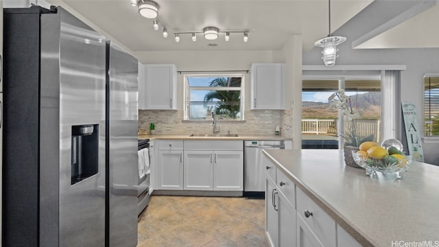 kitchen featuring appliances with stainless steel finishes, sink, backsplash, hanging light fixtures, and white cabinets