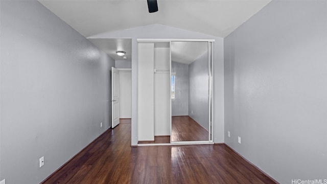 unfurnished bedroom with lofted ceiling, dark wood-type flooring, a closet, and ceiling fan