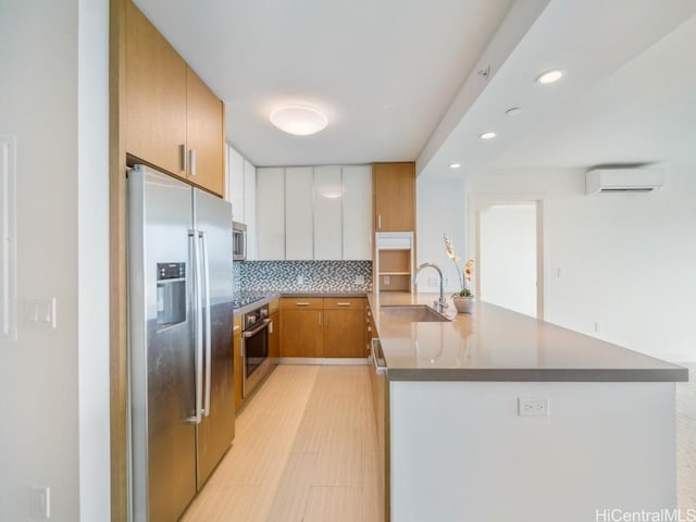 kitchen featuring sink, a wall mounted air conditioner, kitchen peninsula, white cabinets, and appliances with stainless steel finishes