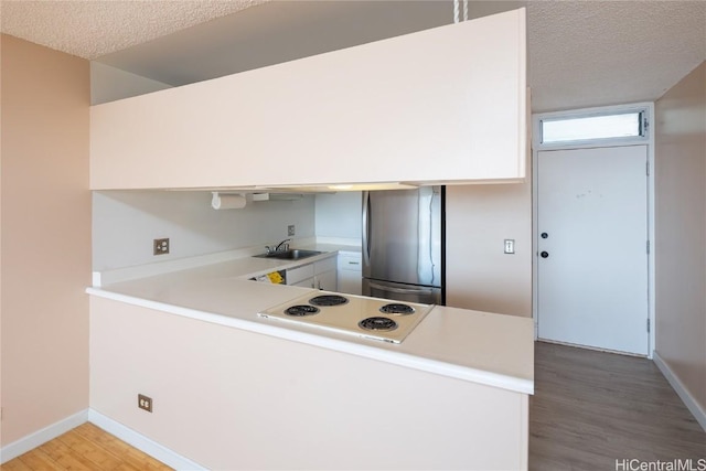 kitchen featuring stainless steel refrigerator, a textured ceiling, and kitchen peninsula