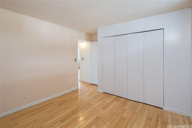 unfurnished bedroom with a textured ceiling, a closet, and light hardwood / wood-style floors