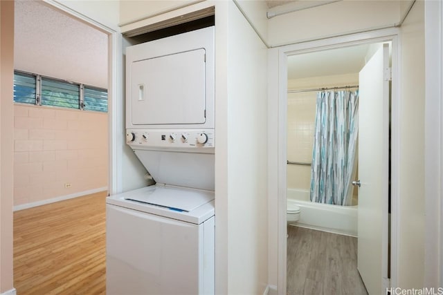 washroom featuring stacked washer and dryer and light hardwood / wood-style flooring