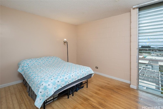 bedroom with a textured ceiling and wood-type flooring