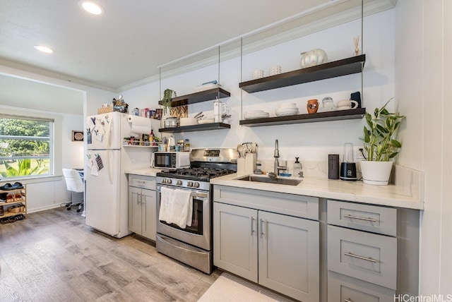 kitchen featuring gray cabinetry, sink, stainless steel range with gas stovetop, crown molding, and light hardwood / wood-style flooring