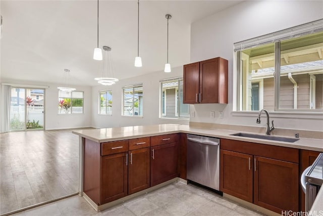 kitchen featuring kitchen peninsula, dishwasher, pendant lighting, stove, and sink