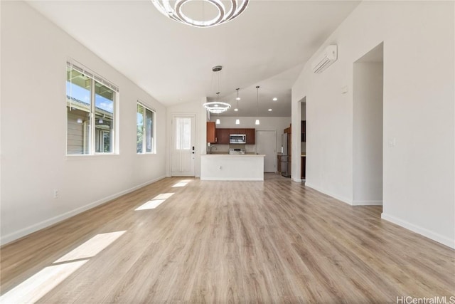 unfurnished living room with light hardwood / wood-style floors, an inviting chandelier, and vaulted ceiling