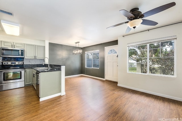 kitchen featuring hardwood / wood-style floors, stainless steel appliances, hanging light fixtures, and sink