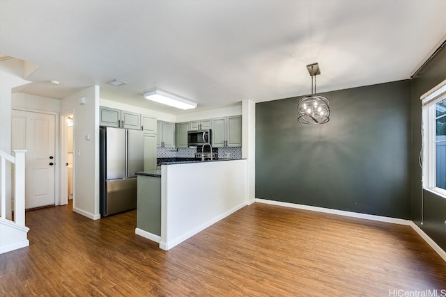 kitchen with hardwood / wood-style flooring, hanging light fixtures, stainless steel appliances, backsplash, and sink