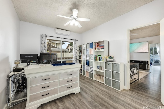 home office with hardwood / wood-style floors, ceiling fan, an AC wall unit, and a textured ceiling