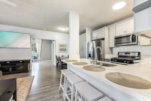 kitchen featuring white cabinetry, light stone counters, a textured ceiling, and appliances with stainless steel finishes