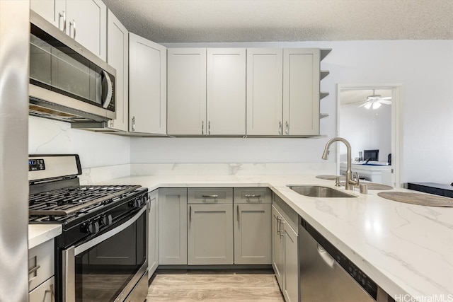 kitchen with ceiling fan, gray cabinets, sink, and stainless steel appliances