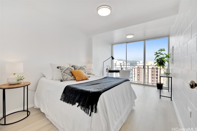 bedroom with expansive windows, light hardwood / wood-style flooring, and access to outside