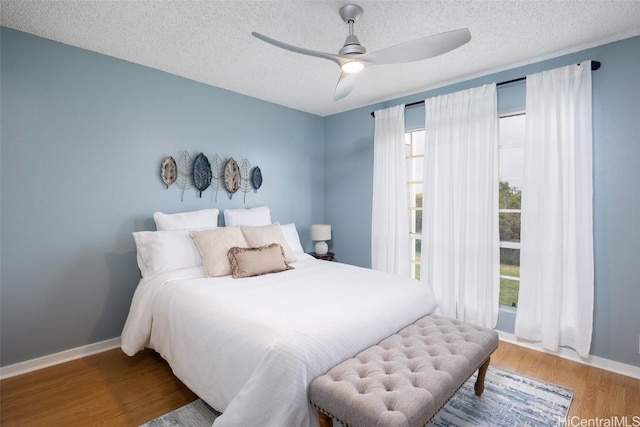 bedroom with ceiling fan, hardwood / wood-style floors, and a textured ceiling