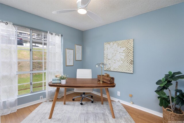 office area featuring baseboards, wood finished floors, a textured ceiling, and ceiling fan
