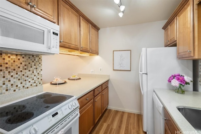 kitchen featuring decorative backsplash, light hardwood / wood-style floors, white appliances, and track lighting