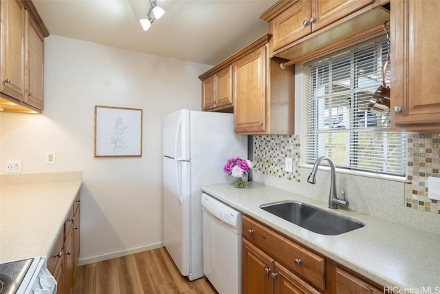 kitchen with backsplash, white dishwasher, range, and a sink