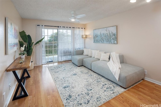 living room featuring ceiling fan, wood-type flooring, and a textured ceiling