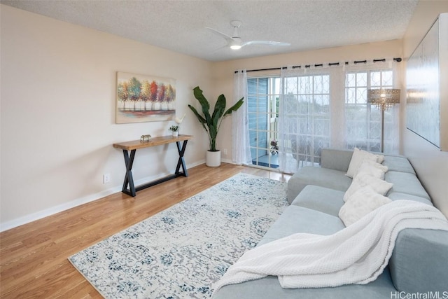 living room with a textured ceiling, light hardwood / wood-style flooring, and ceiling fan