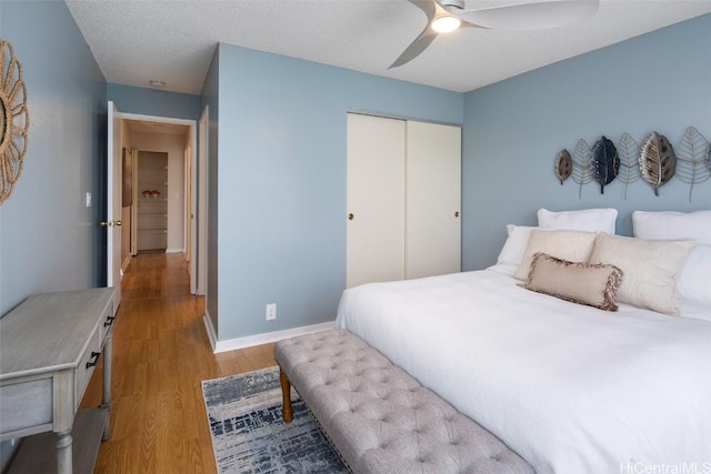 bedroom featuring a textured ceiling, a closet, light hardwood / wood-style floors, and ceiling fan