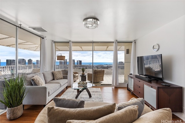 living room featuring dark hardwood / wood-style floors, expansive windows, a water view, and an inviting chandelier