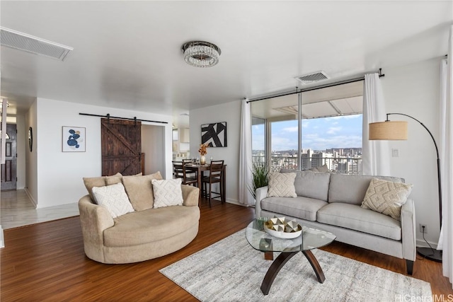 living area with a barn door, wood finished floors, visible vents, and a city view