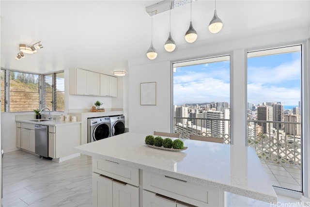 kitchen with stainless steel dishwasher, washing machine and clothes dryer, hanging light fixtures, light stone countertops, and white cabinets