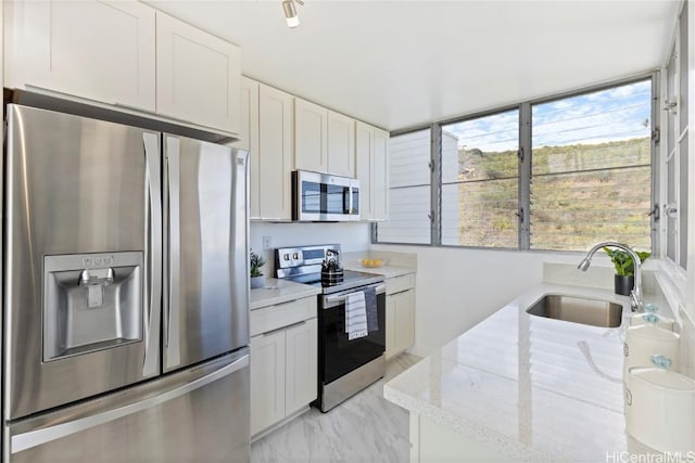 kitchen with light stone counters, marble finish floor, appliances with stainless steel finishes, white cabinetry, and a sink