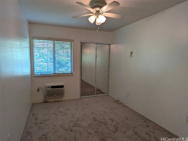 unfurnished bedroom with a wall unit AC, a closet, light colored carpet, and ceiling fan