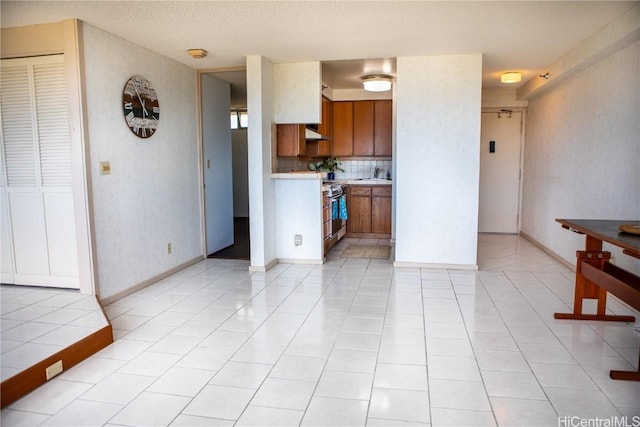 kitchen featuring stainless steel electric stove, tasteful backsplash, sink, light tile patterned floors, and a textured ceiling