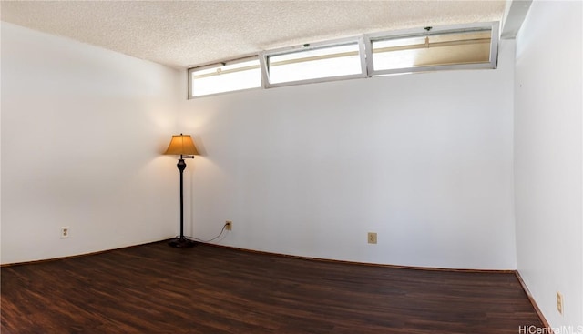 empty room featuring a textured ceiling and dark hardwood / wood-style floors