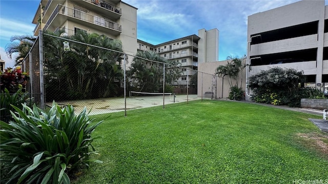 view of community featuring tennis court and a yard