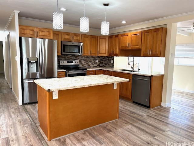 kitchen featuring appliances with stainless steel finishes, a center island, sink, and hanging light fixtures