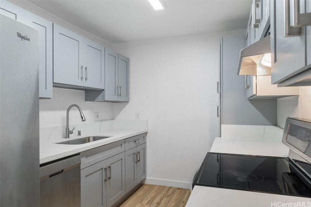 kitchen with gray cabinets, stainless steel appliances, sink, and light wood-type flooring