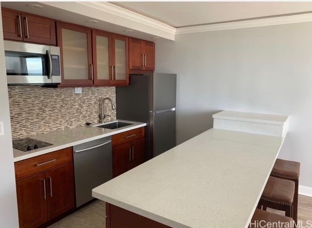 kitchen featuring decorative backsplash, a breakfast bar area, sink, crown molding, and stainless steel appliances