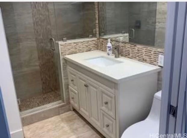 bathroom with vanity, toilet, walk in shower, and decorative backsplash