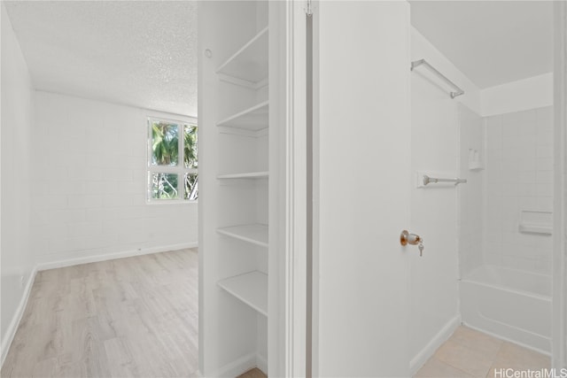 bathroom with washtub / shower combination, a textured ceiling, and wood-type flooring