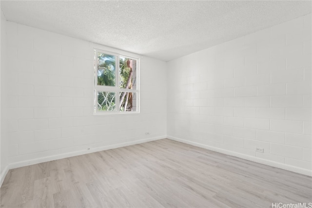 spare room with a textured ceiling and light hardwood / wood-style flooring