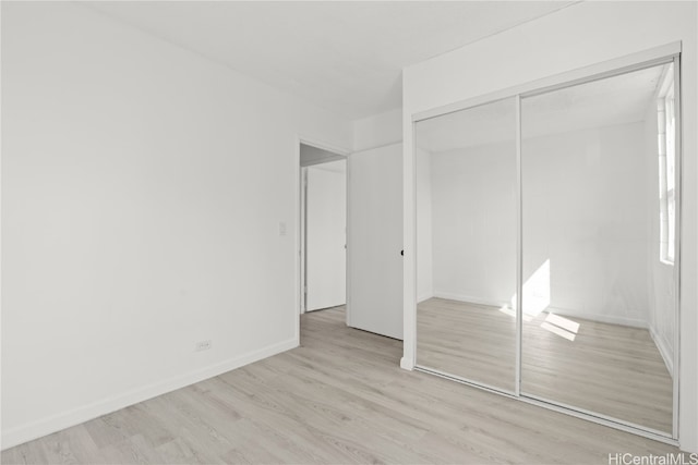 unfurnished bedroom with a closet and light hardwood / wood-style floors