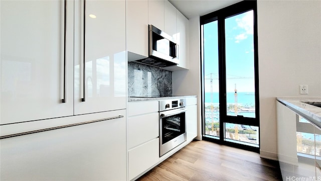 kitchen featuring appliances with stainless steel finishes, decorative backsplash, white cabinetry, and a wealth of natural light