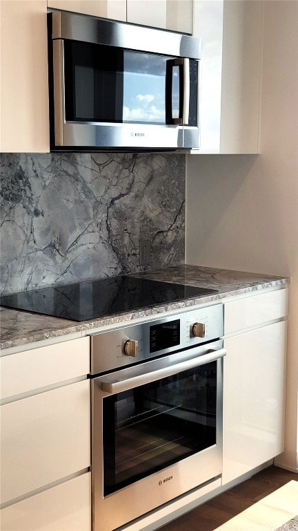 kitchen with light stone countertops, appliances with stainless steel finishes, and white cabinets