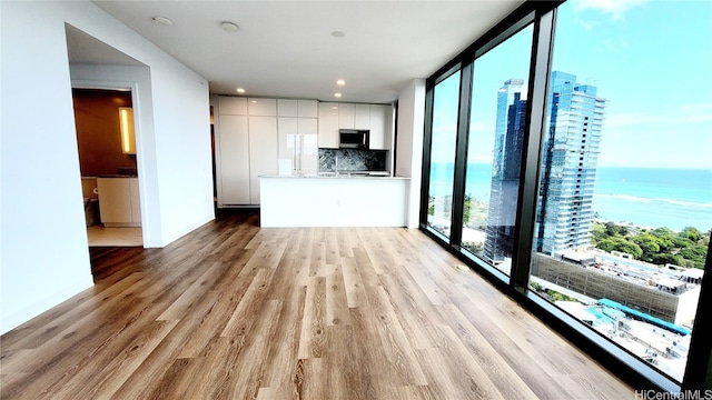 unfurnished living room with a water view and light wood-type flooring