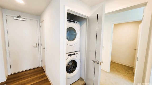 clothes washing area featuring stacked washer and dryer and wood-type flooring