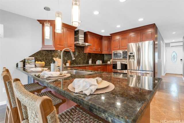 kitchen featuring sink, hanging light fixtures, wall chimney exhaust hood, kitchen peninsula, and stainless steel appliances