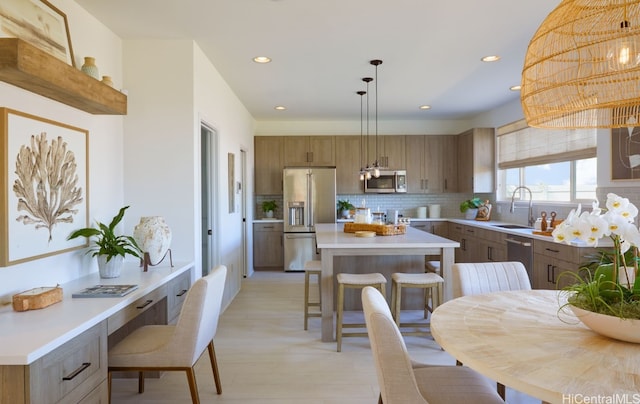 kitchen with a kitchen island, stainless steel appliances, backsplash, sink, and pendant lighting