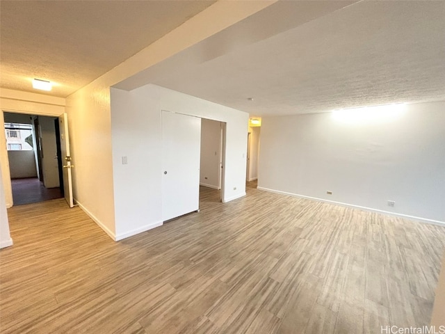 empty room featuring a textured ceiling and light hardwood / wood-style flooring