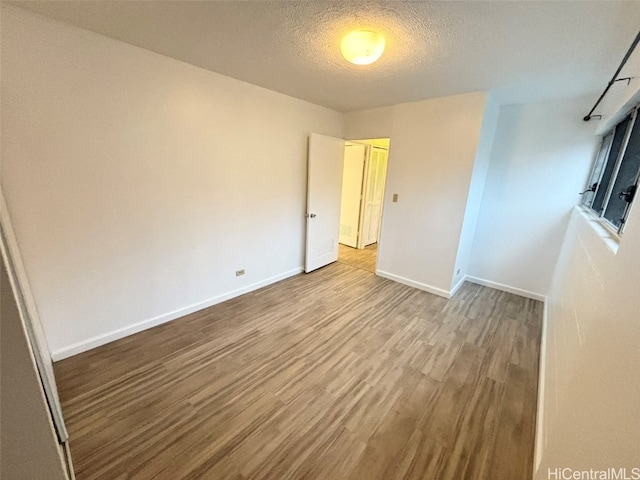 spare room with a textured ceiling and hardwood / wood-style floors