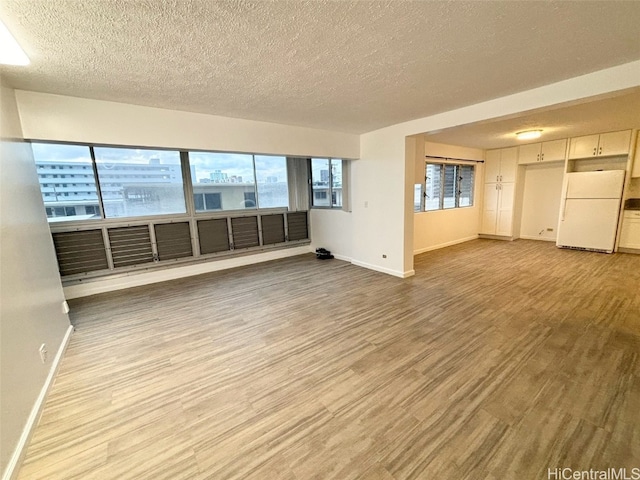 unfurnished living room with a textured ceiling, wood-type flooring, and a wealth of natural light