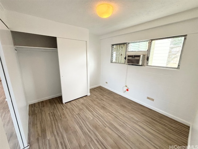 unfurnished bedroom featuring hardwood / wood-style floors, cooling unit, a textured ceiling, and a closet