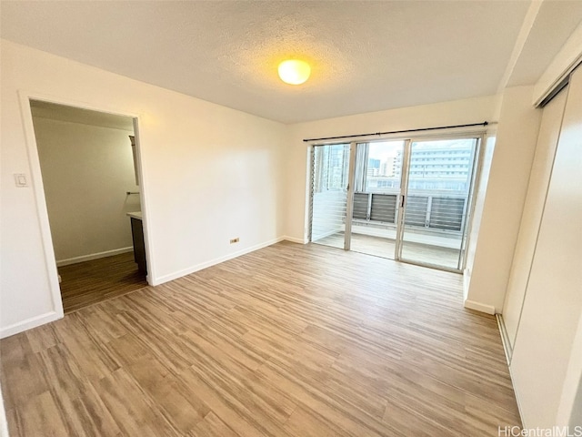 empty room featuring light hardwood / wood-style floors and a textured ceiling