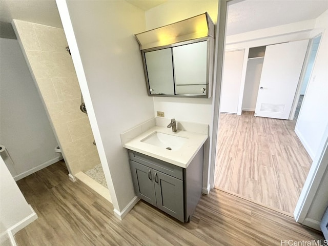 bathroom with vanity, toilet, hardwood / wood-style flooring, and walk in shower